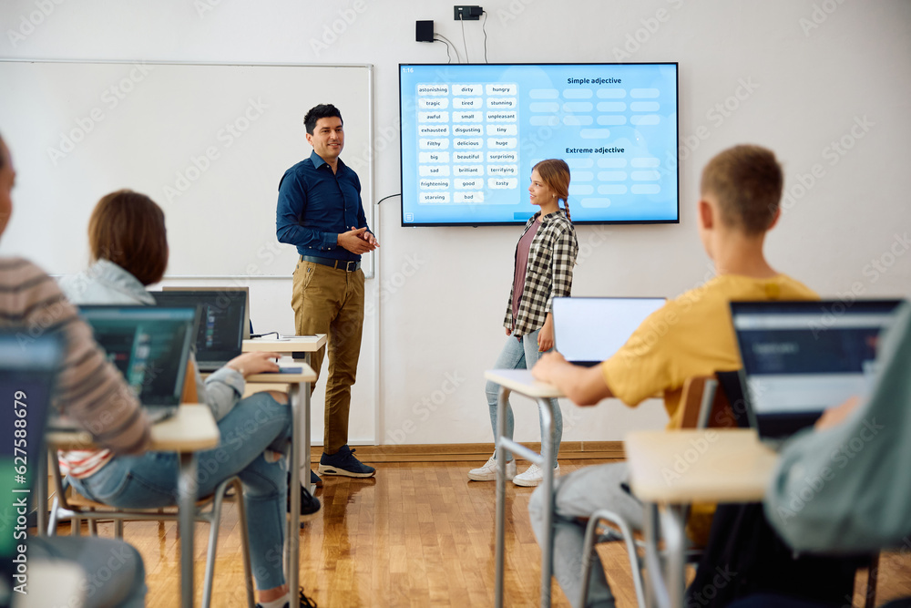 Male teacher and his students using interactive whiteboard during class at high school.